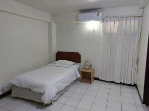 een witte slaapkamer met een bed en een raam bij Baan Sathorn 21 in Yan Nawa