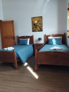 Dos camas en una habitación con sábanas azules. en Quinta da Fonte, en Torneira