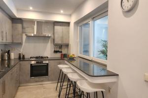 波托什The Lemon Tree的厨房配有带凳子的柜台和时钟