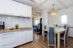 a kitchen and dining room with white cabinets and a table at Major S - Domek in Gdańsk