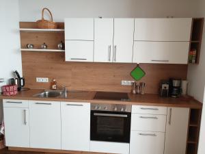 a kitchen with white cabinets and a sink at Ferienwohnung unterhalb der Heidecksburg in Rudolstadt