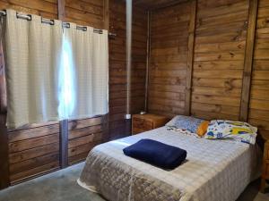 ein Schlafzimmer mit einem Bett in einer Holzhütte in der Unterkunft Chalé na serra da mantiqueira in Piranguçu