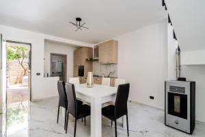 cocina blanca con mesa blanca y sillas negras en Casa Chiaraluna by BarbarHouse, en Porto Cesareo