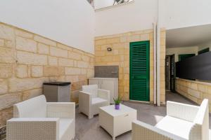 un patio con sillas blancas y una puerta verde en Casa Chiaraluna by BarbarHouse, en Porto Cesareo