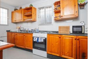 Una cocina con gabinetes de madera y un horno de estufa. en Casita rural de invitados, en Alcalá de Guadaira