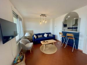 salon z niebieską kanapą i stołem w obiekcie Joli 3 Pièces rénové avec terrasse, vue mer et ascenseur - FR-1-716-2 w mieście La Grande-Motte