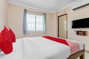 ein Schlafzimmer mit einem Bett mit roten Kissen und einem Fernseher in der Unterkunft PN SAMY INN in Puducherry + 14 Fotos