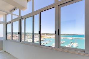 ein Zimmer mit Fenstern mit Blick auf einen Hafen in der Unterkunft Appartamento La Perla Luxury - MyHo Casa in Vieste