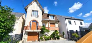 une grande maison blanche avec une clôture noire dans l'établissement Konforta : Paisible maison d'été avec grand jardin, à Sainte-Geneviève-des-Bois