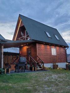ein großes Holzhaus mit einem Grill davor in der Unterkunft Domek Przystan kajakowa in Zwierzyniec