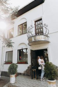 a woman holding a baby in front of a building at Eduard Hotel in Uzhhorod