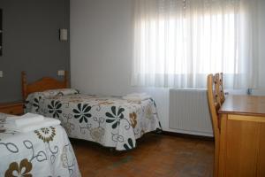 納瓦萊諾的住宿－Hostal La Tablada，客房设有两张床、一张桌子和一个窗户。