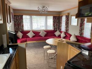 a living room with a red couch and a table at Three bed static caravan with fantastic views and hottub in Swansea