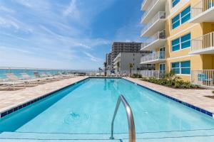 a swimming pool with chairs and the ocean in the background at Unit 103 Aruba - 3 Bedroom Ocean Front in Daytona Beach