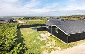 a house with a black roof on the beach at 2 Bedroom Stunning Home In Hjørring in Hjørring +8 photos