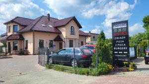 a car parked in front of a house with a sign at Noclegi Avoca in Pyrzowice