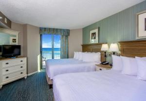 a hotel room with two beds and a television at The Strand - A Boutique Resort in Myrtle Beach +37 photos