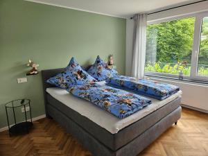 ein Schlafzimmer mit einem Bett mit blauen Kissen und einem Fenster in der Unterkunft Schorn³ Appartements in Zell an der Mosel