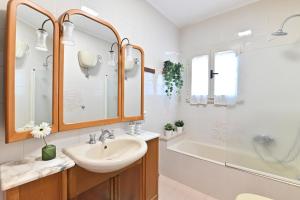 a bathroom with a sink and a tub and a mirror at IzzHome Central in Pula