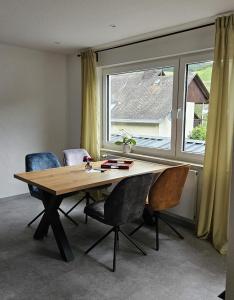 einen Esstisch mit Stühlen und ein großes Fenster in der Unterkunft Schorn³ Appartements in Zell an der Mosel