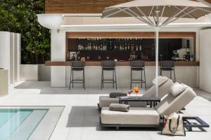 eine Terrasse mit einer Bar mit Couch und Sonnenschirm in der Unterkunft Blazer Suites Hotel in Athen