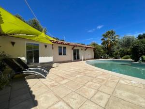 a house with a swimming pool and a yellow umbrella at T2 piscine proche plage in Carqueiranne +4 photos