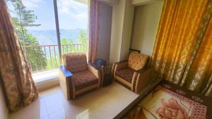 a room with two chairs and a balcony with a window at Aqua Apartment Murree in Murree