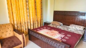 a small bedroom with a bed and a chair at Aqua Apartment Murree in Murree