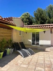 a patio with two chairs and a yellow umbrella at T2 piscine proche plage in Carqueiranne