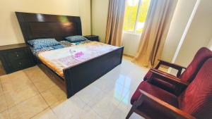 a bedroom with a large bed and a chair at Aqua Apartment Murree in Murree