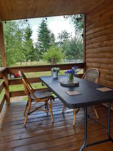 a black table and chairs on a wooden deck at Chatka nad Stawami in Bierdzież