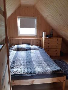 a bedroom with a bed in a attic with a window at Chatka nad Stawami in Bierdzież