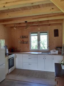 a kitchen with white cabinets and a window at Chatka nad Stawami in Bierdzież +17 photos