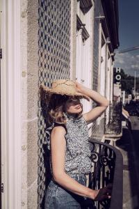 比索達雷加的住宿－Original Douro Hotel，坐在阳台上戴草帽的女人