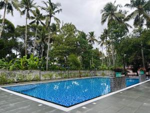 a swimming pool in a resort with palm trees at LEISURE VALLEY BEACH RESORT in Varkala