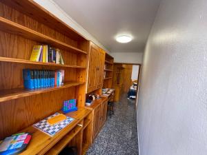 Una oficina con estantes de madera y escritorios con libros. en Vivienda Vacacional C & M, en Puerto del Rosario
