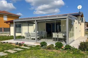 a conservatory with glass doors and chairs on a patio at Il Giardino di Sofia B&B in Piozzo