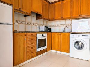 une cuisine avec des armoires en bois et une laveuse et une sécheuse dans l'établissement Apartamento turístico en Son Bou con vistas al mar, à Son Bou