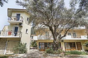 un immeuble d'appartements avec un arbre devant dans l'établissement Mezoneta 1, à Nydri