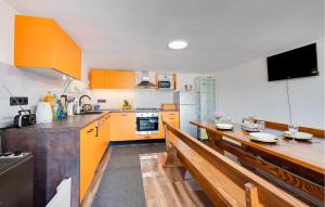 a kitchen with orange cabinets and a table and benches at Beautiful Home In Stubicka Slatina in Stubička Slatina