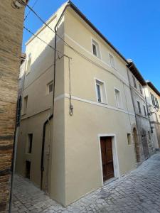 a large white building with a door on a street at Maison62 in San Severino Marche