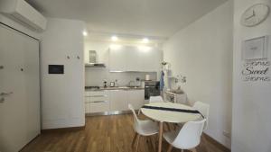 a white kitchen with a table and white chairs at Appartamento sul mare Nettuno in Nettuno