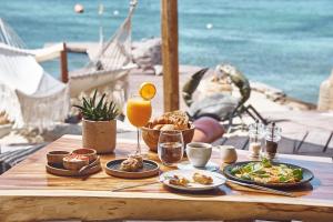 a table with plates of food and a glass of orange juice at Hippie Chic Hotel in Agios Ioannis Mykonos