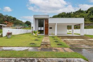 a small white house with a grass yard at Refúgio 4 Suítes em São Miguel dos Milagres in São Miguel dos Milagres