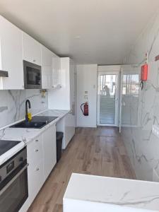 a kitchen with white cabinets and a wooden floor at Lisbon South Bay Rooms 2 in Almada