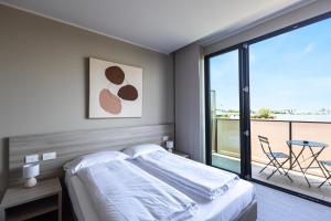a bedroom with a bed and a balcony with a table at Virtual - Superior Apartments Milano Opera in Opera +44 photos