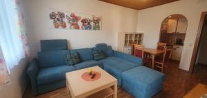 a living room with a blue couch and a table at Apartments Jacqueline in Sankt Kanzian