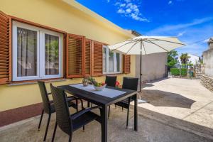 a table and chairs with an umbrella on a patio at Holliday house Smokvica in Jadranovo