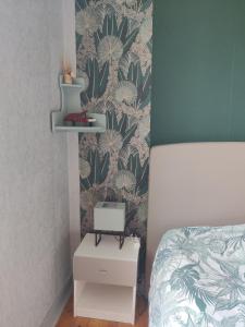 a bedroom with a bed and a wall with a plant wallpaper at charmante chambre chez l'habitant in Montfort-le-Gesnois +4 photos