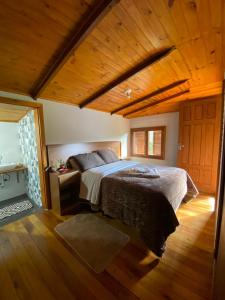 Un dormitorio con una cama grande en una habitación de madera. en Pousada Doce Vida, en Urubici